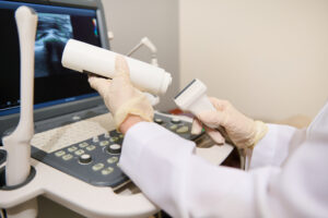 Close-up of the hand of a radiologist doctor holding an ultrasound transducer and contact gel getting ready for a diagnosis. Ultrasonography. USG